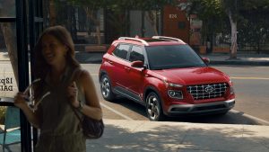 A woman standing inside of a business with the door open to a parked, red 2021 Hyundai Venue. | Hyundai dealer in North Little Rock, AR.