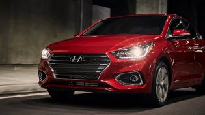 Close view of the front of a red 2022 Hyundai Accent being driven with its lights on. | Hyundai dealer in North Little Rock, AR.