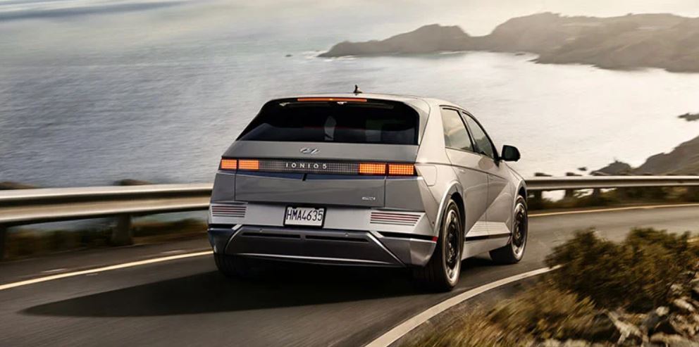 Rear view of a 2022 Hyundai Ioniq Hybrid driving along a scenic coastal road