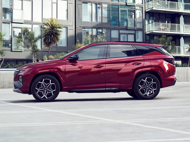 Profile view of a dark red 2023 Hyundai Tucson Hybrid parked in front of an apartment building. | Hyundai dealer in North Little Rock, AR | Crain Hyundai of North Little Rock