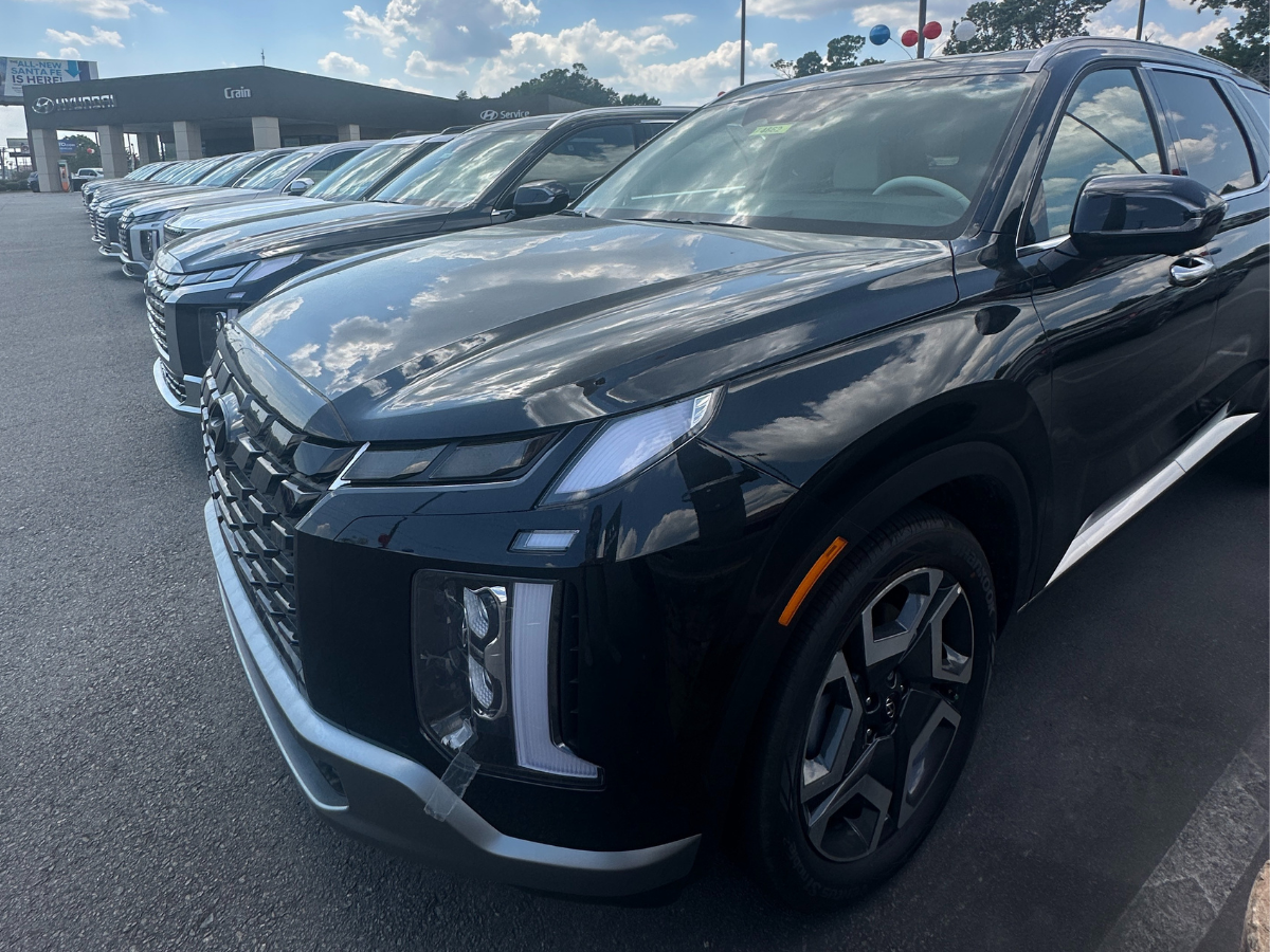 Row of 2025 Hyundai Palisade SUVs at Crain Hyundai of North Little Rock, lined up in the dealership lot under a partly cloudy sky.